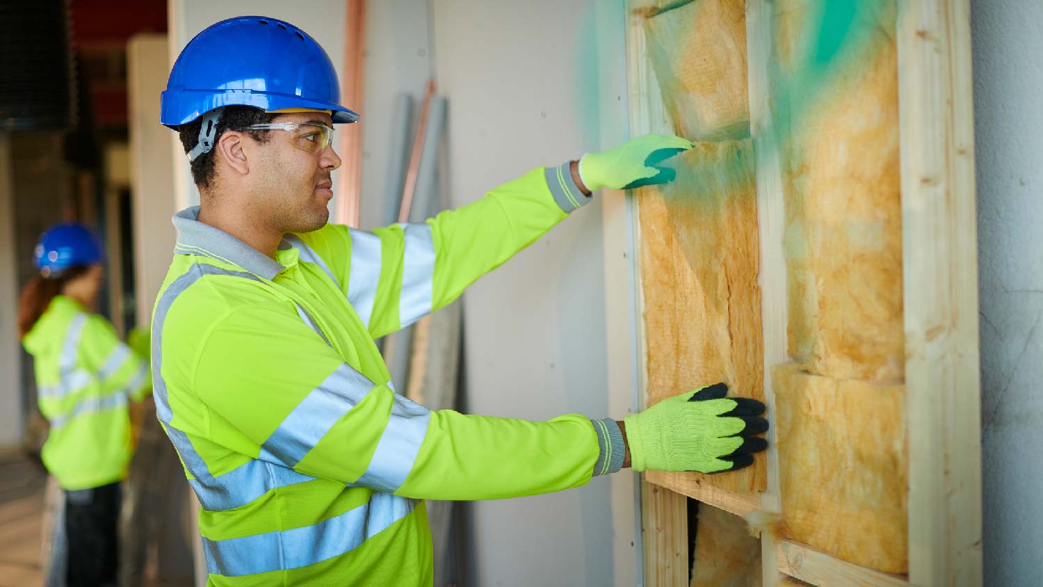 A worker installing fiberglass insulation