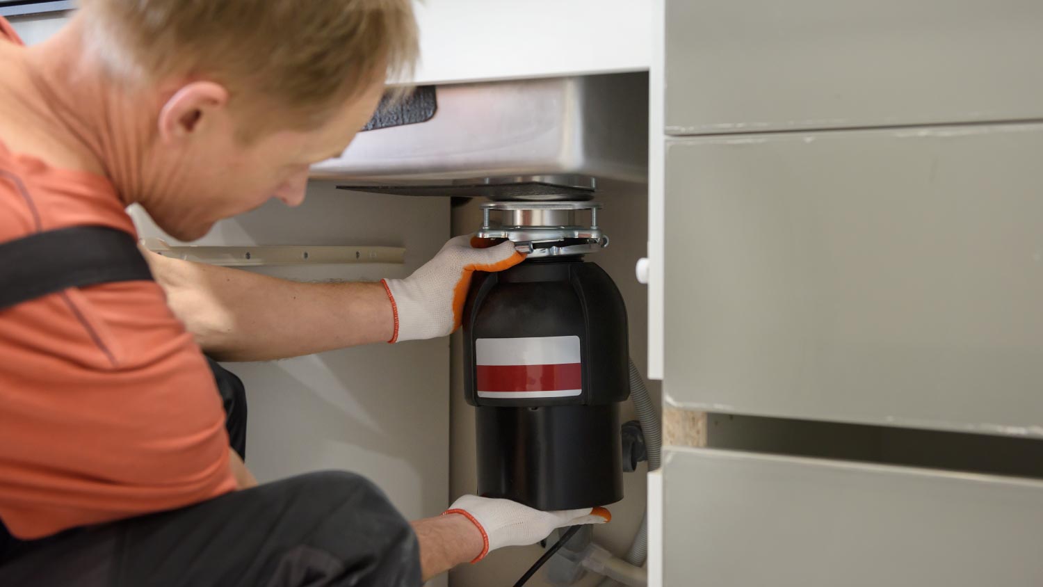 Worker installing a household waste shredder