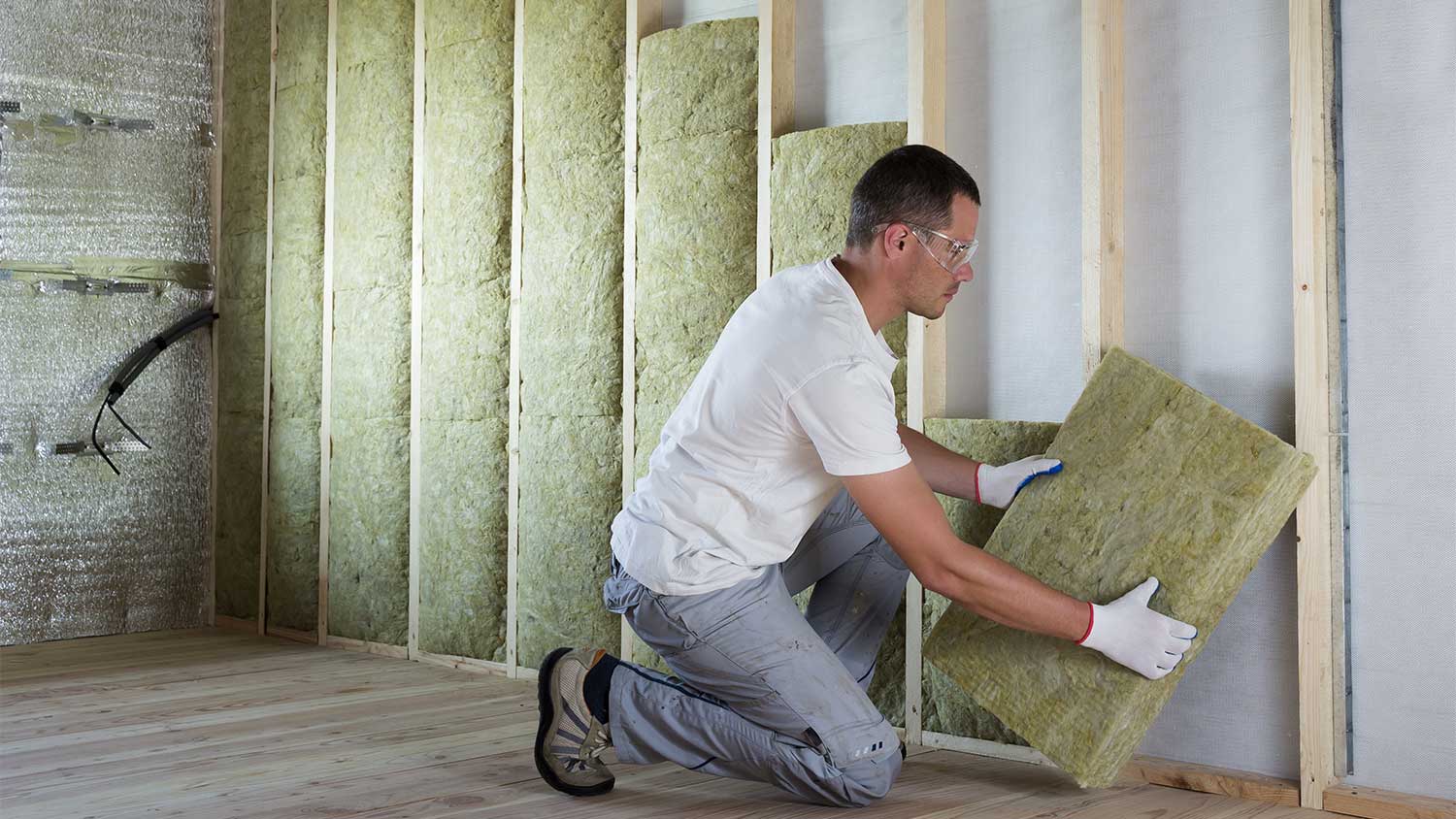 Worker installing wall insulation