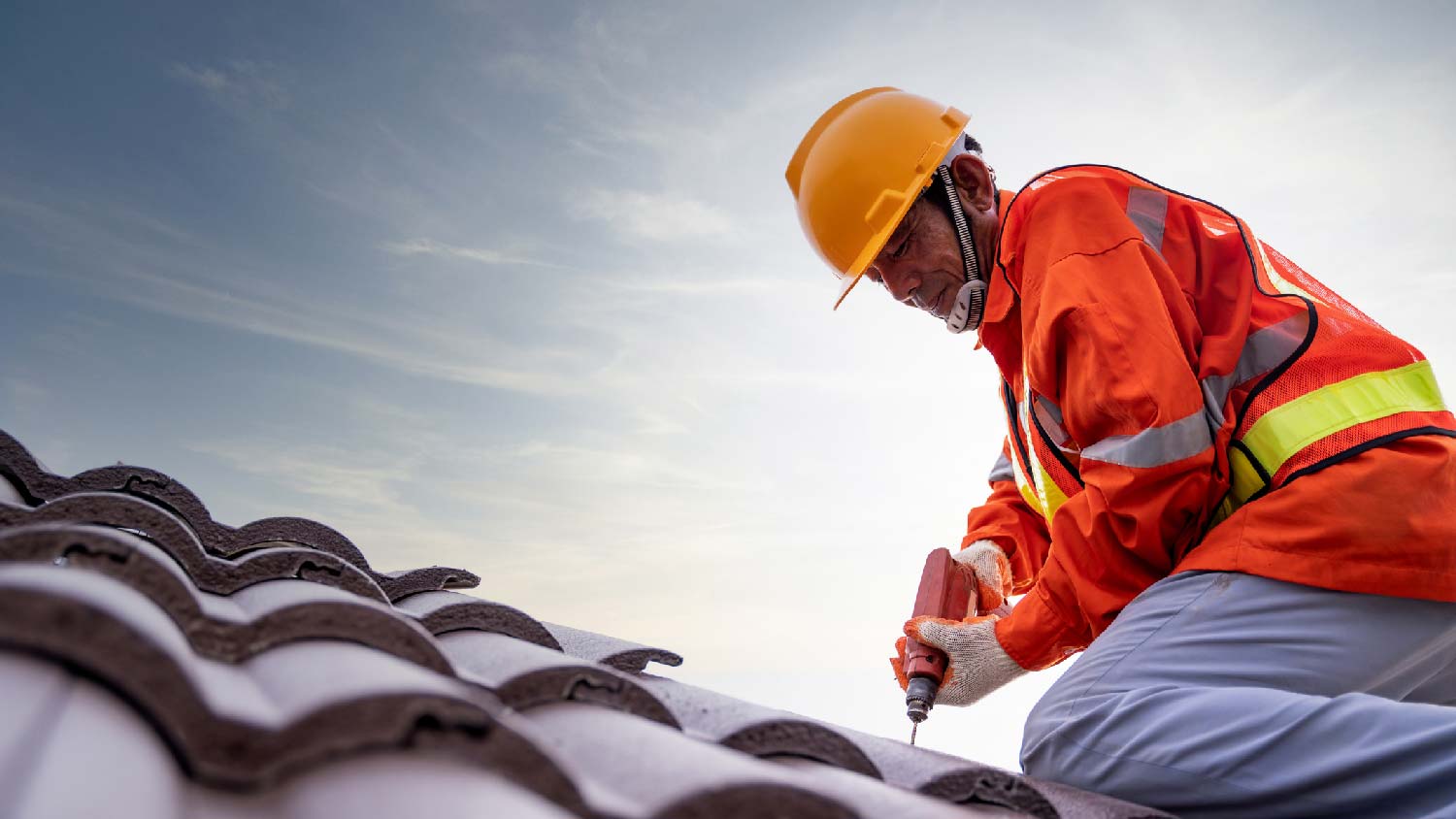 A worker installing shingles on the roof