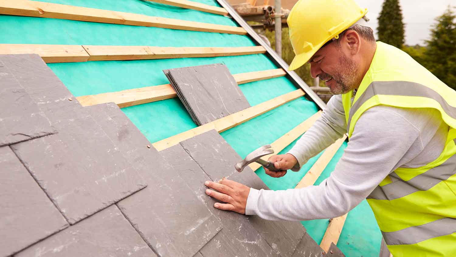 Contractor installing new slate shingles on the roof