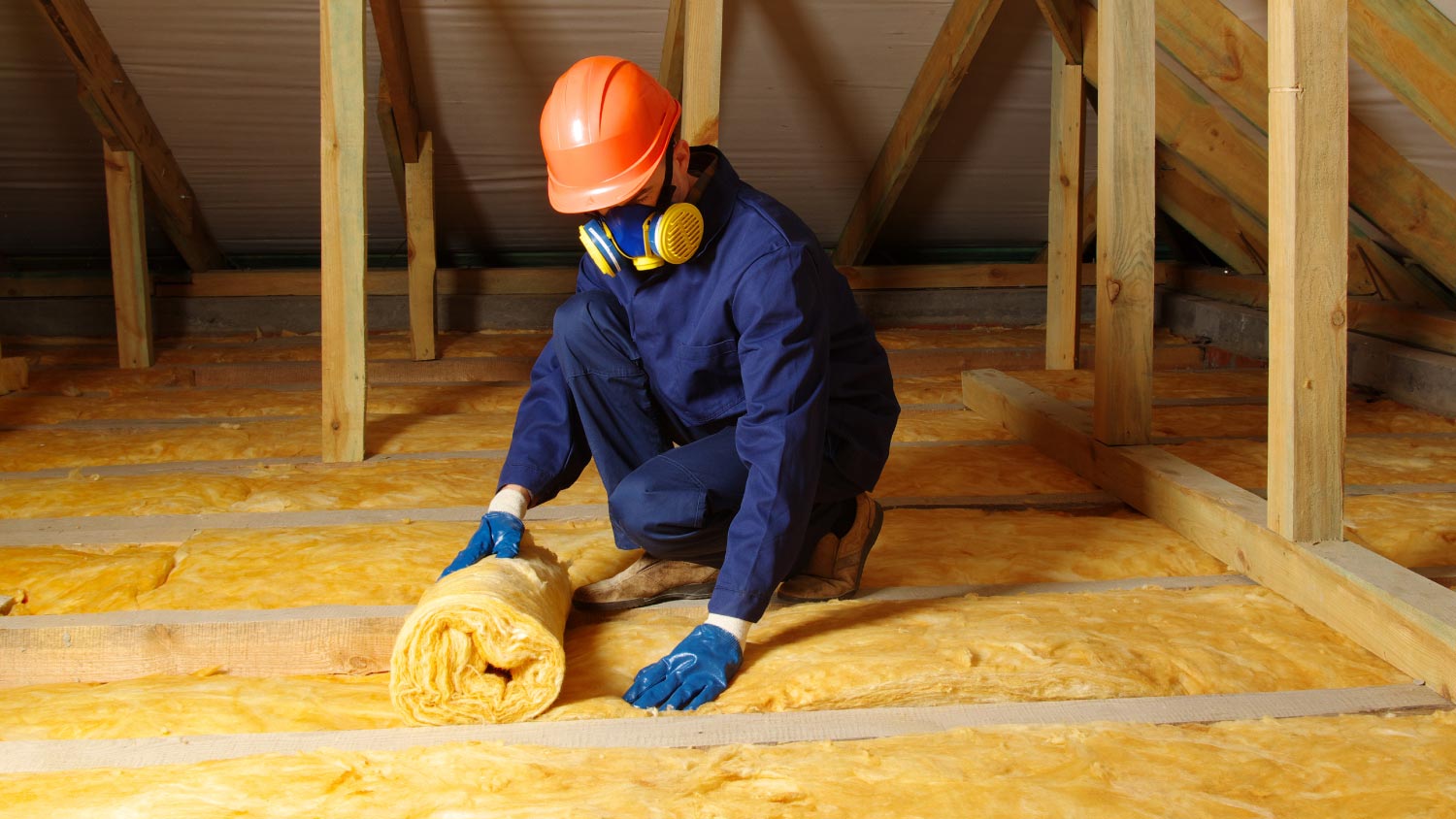A worker insulating attic with mineral wool