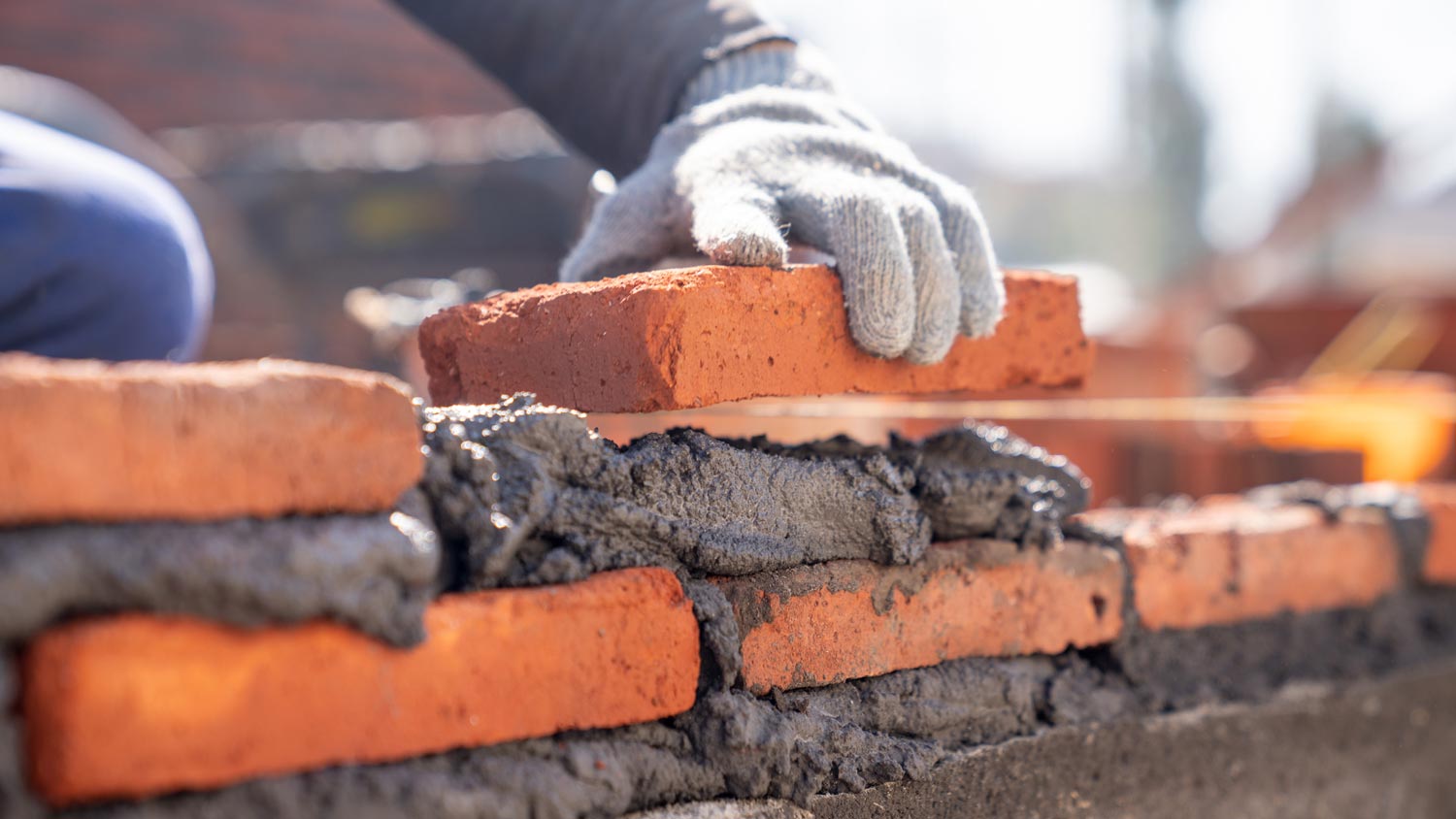 A worker with gloves laying new bricks