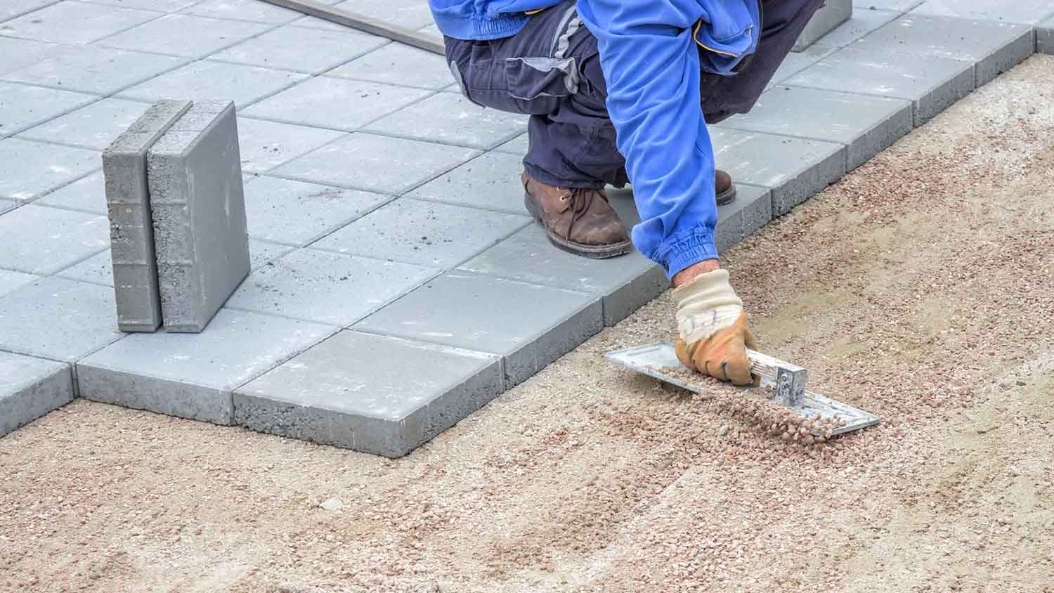 Worker laying gravel to install pavers 