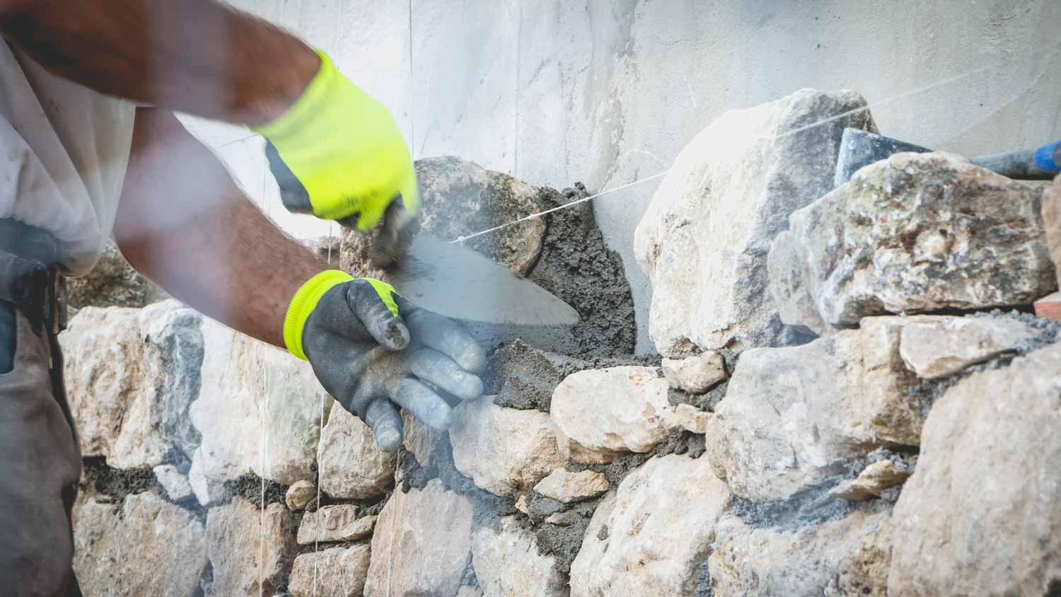 A worker laying mortar on stones