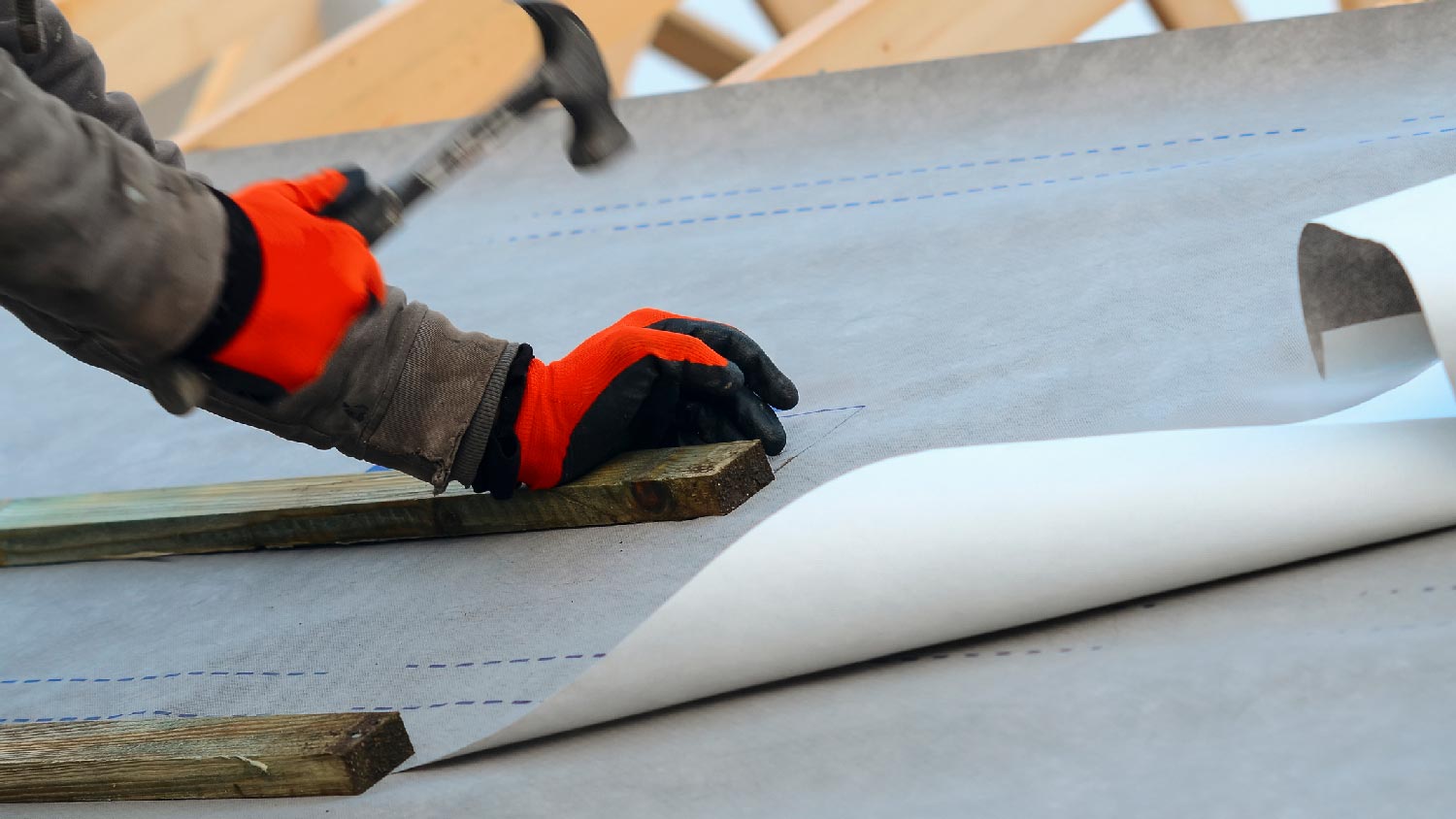 A worker laying synthetic underlayment