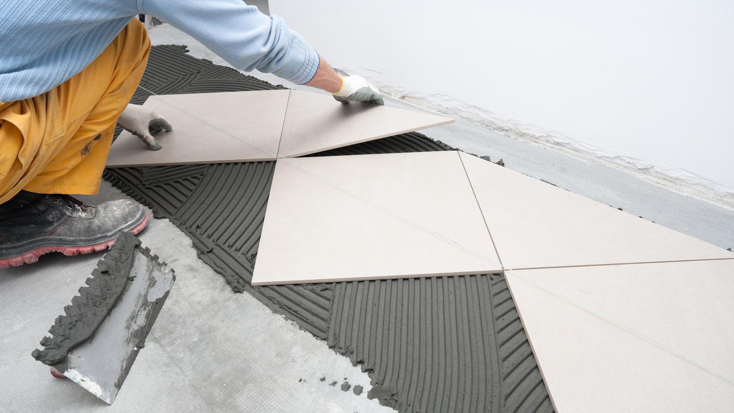 A worker laying tiles over concrete