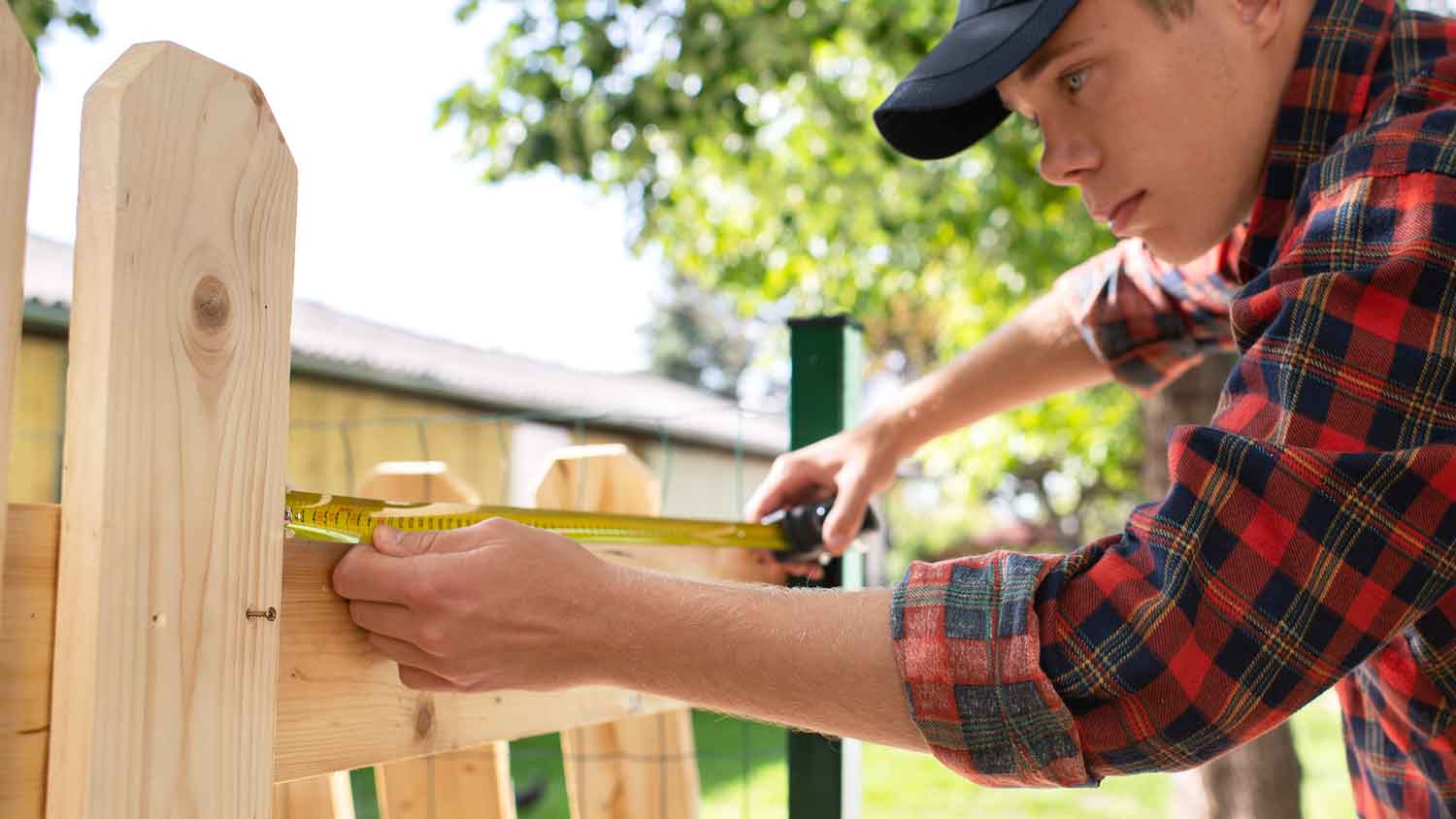 Worker measuring the space between fence pickets