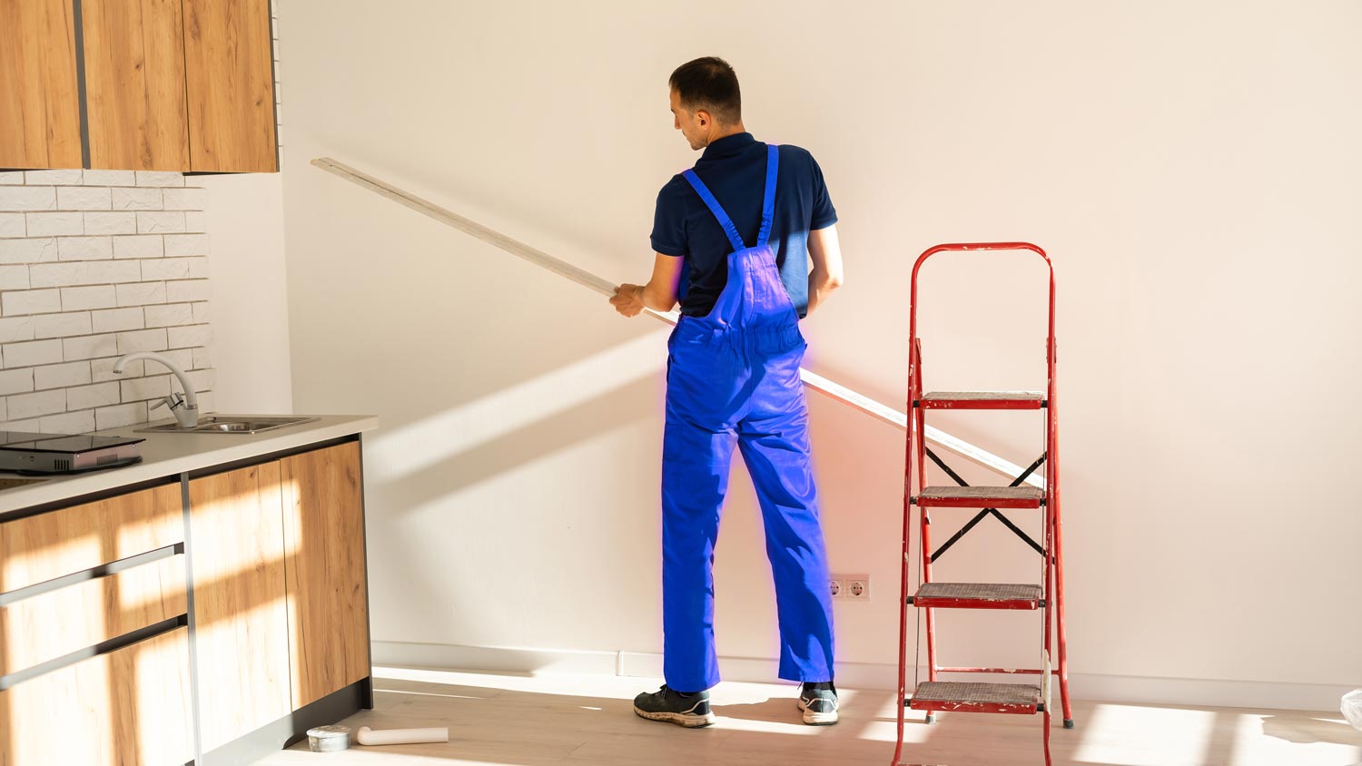 A worker measuring a drywall