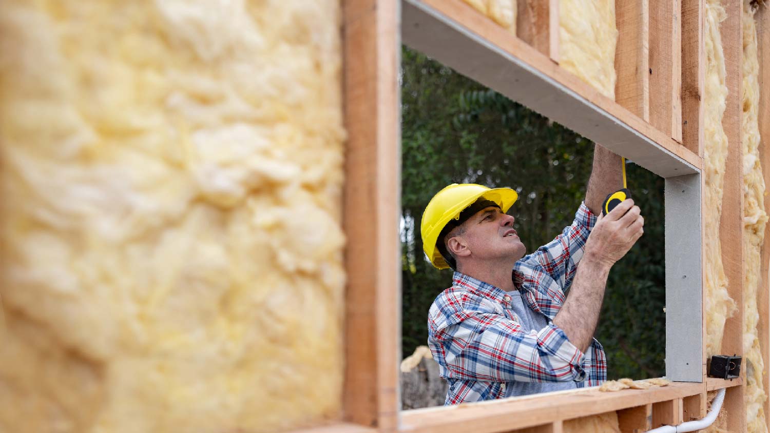 A worker measuring a mobile home’s window