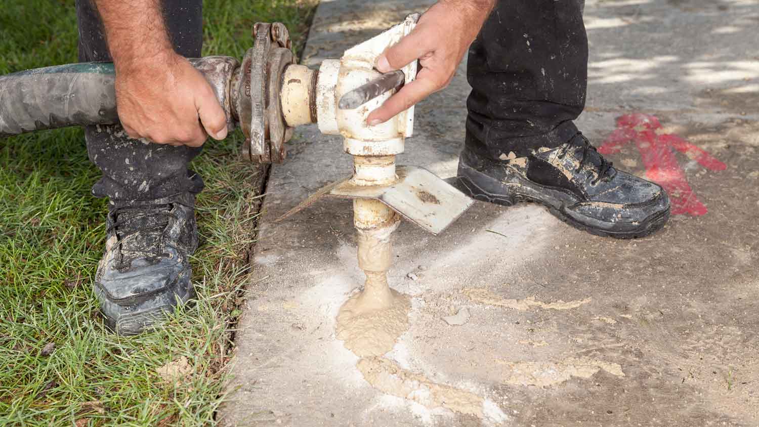 Worker using mudjacking method to level concrete