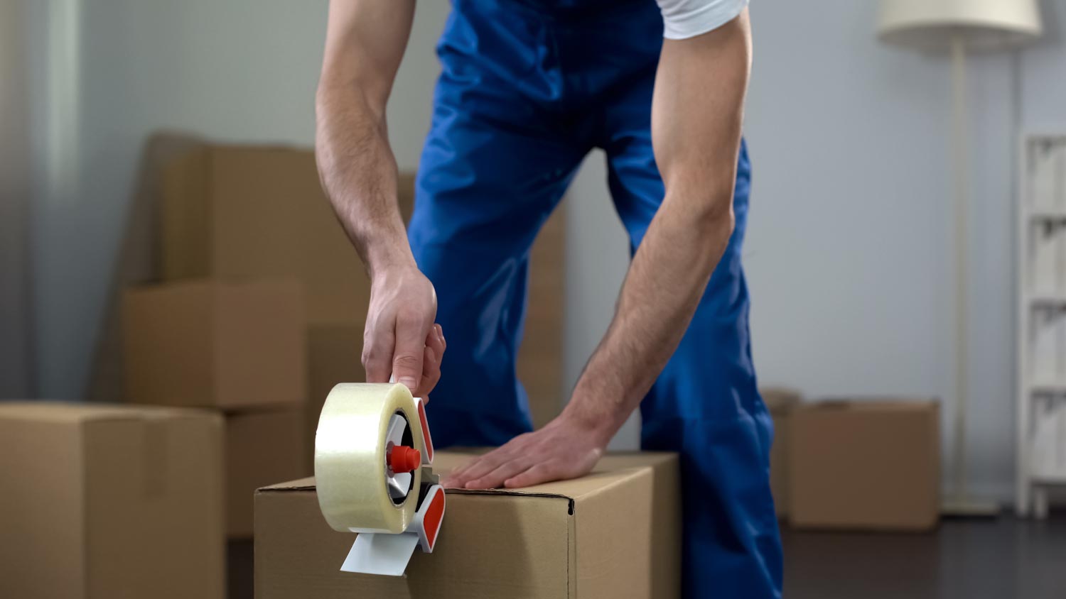 Moving company worker packing cardboard boxes