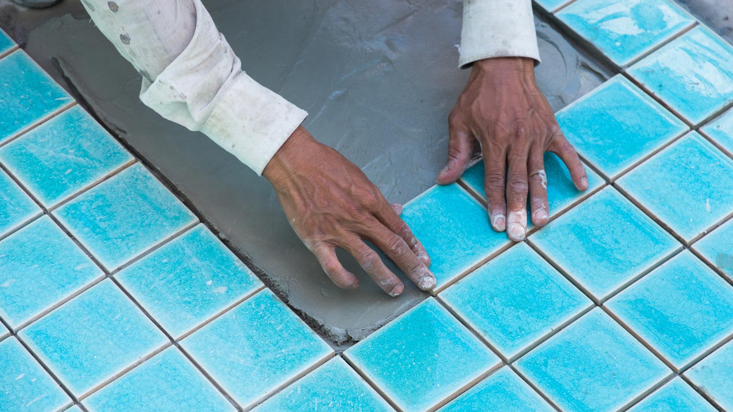 A worker placing new tiles on the pool surface