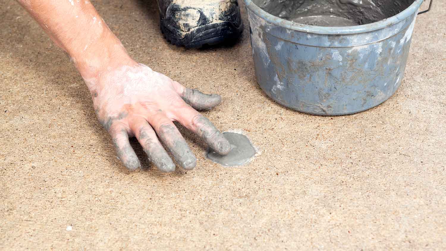 Worker filling in a hole with concrete to refinish a sidewalk