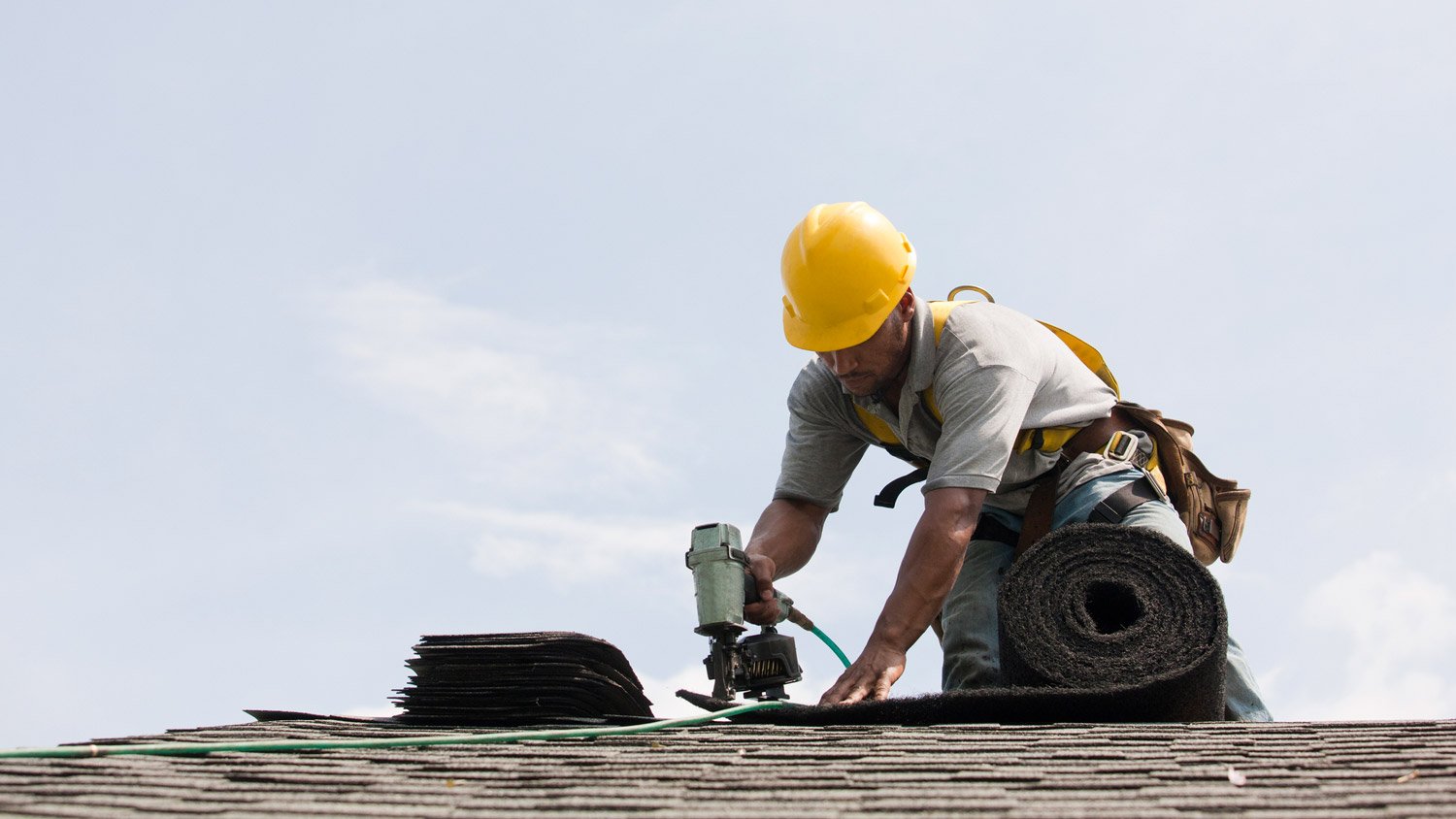 A worker replacing a roof’s shingles