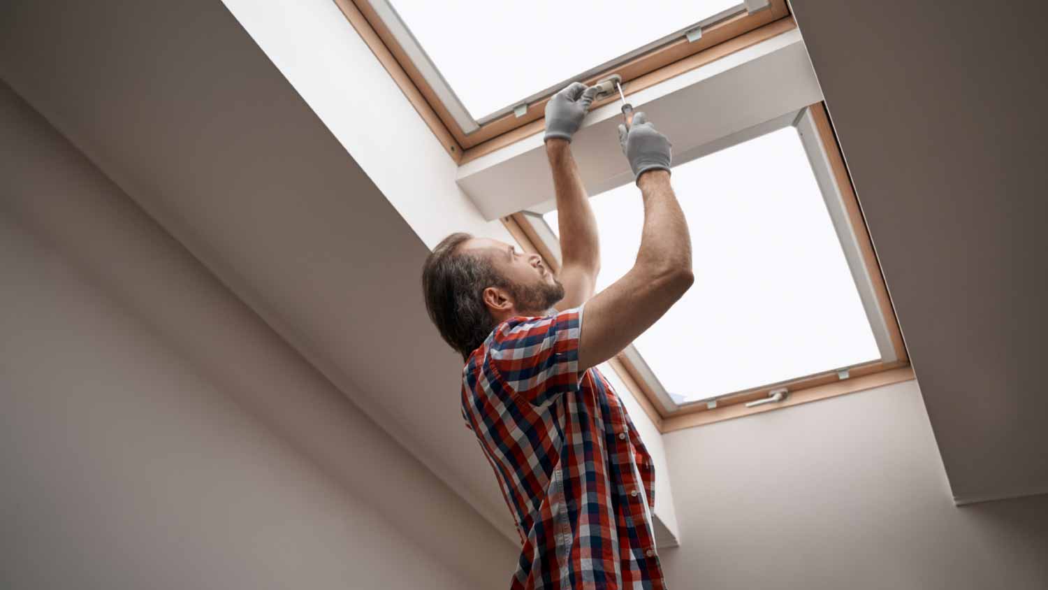 Worker screwing skylight window