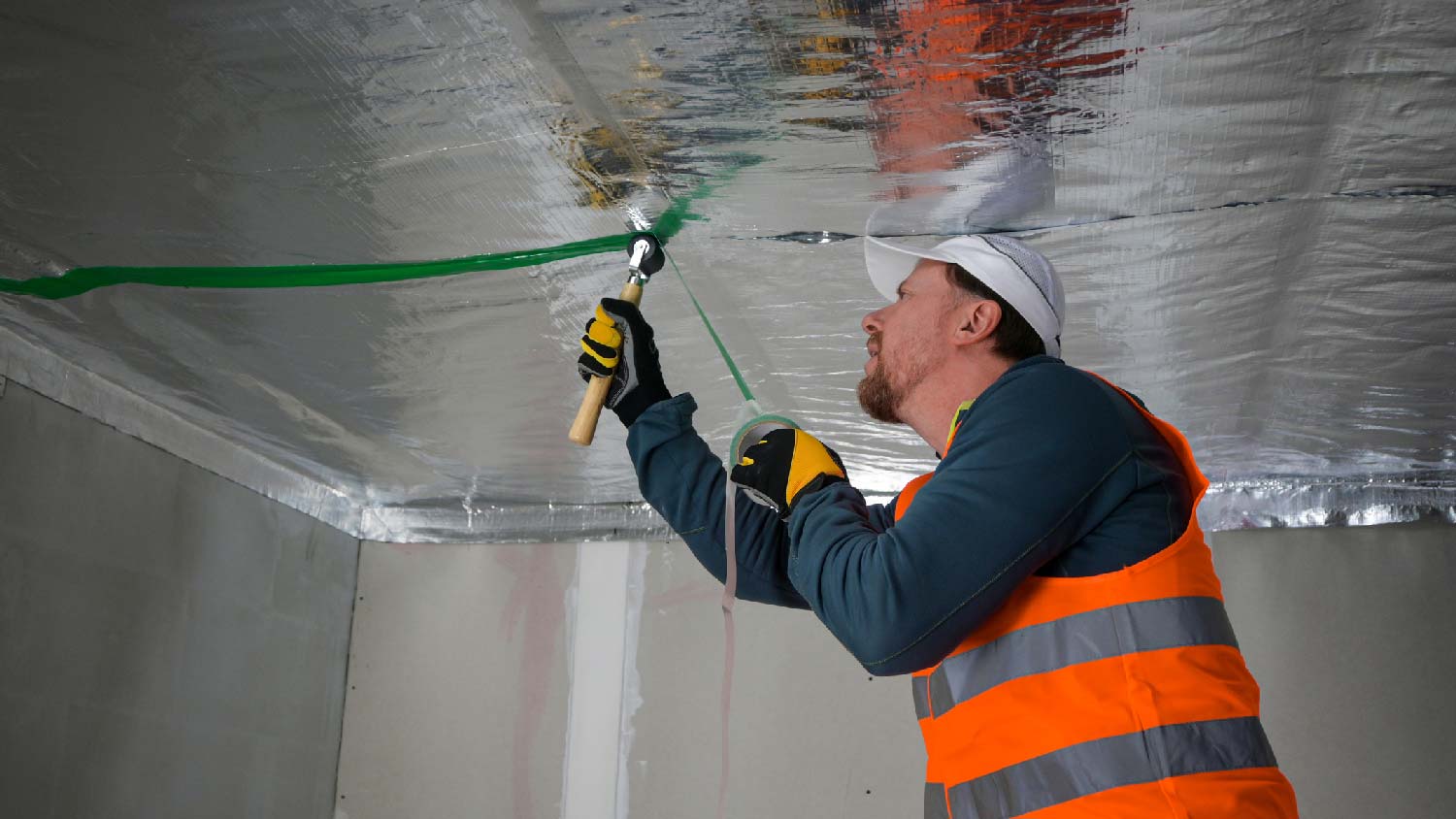 A worker soundproofing a ceiling