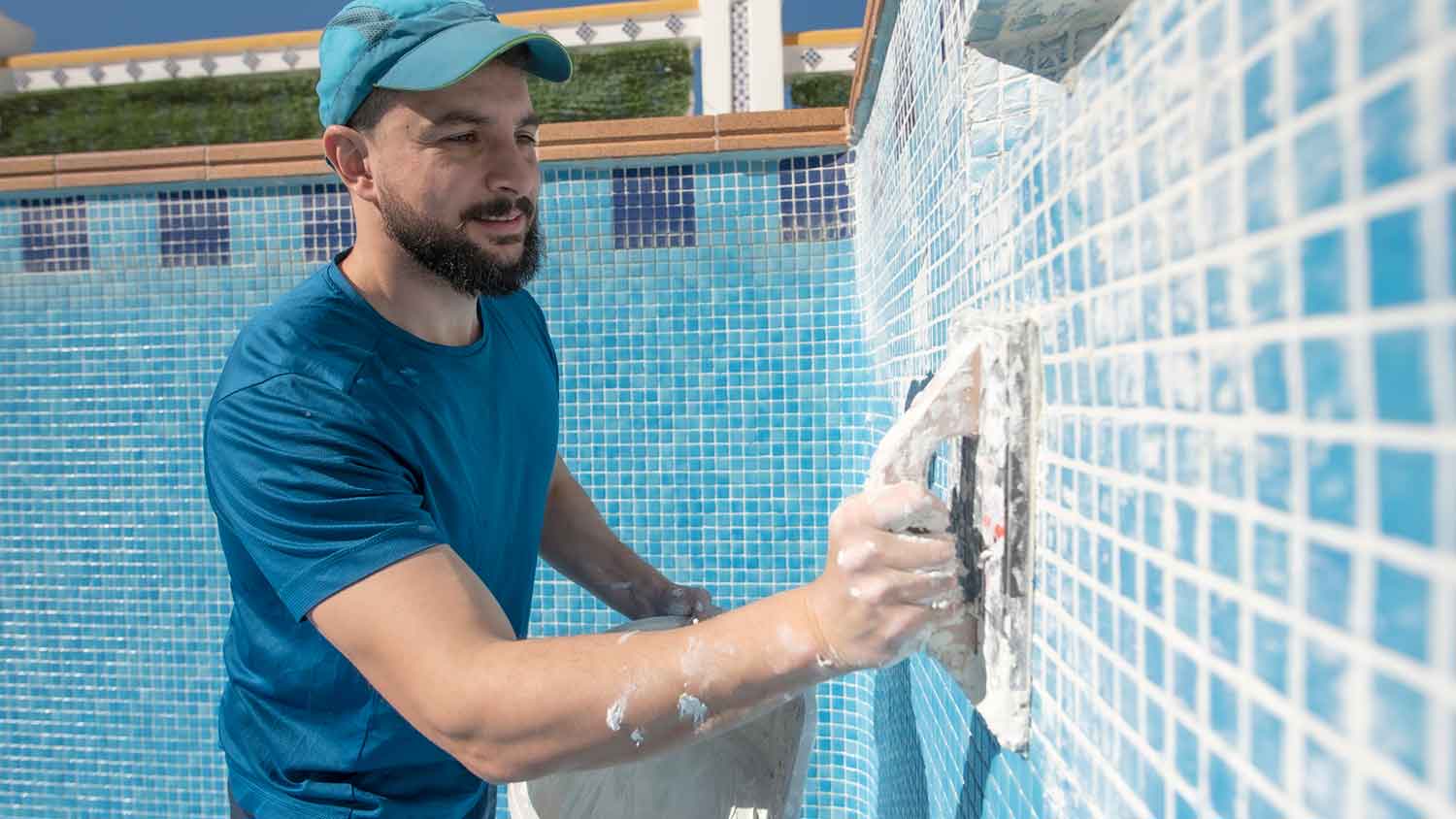 Worker installing tiles in the swimming pool