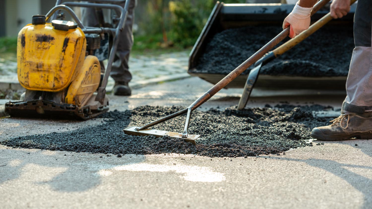 Workers arranging fresh asphalt mix