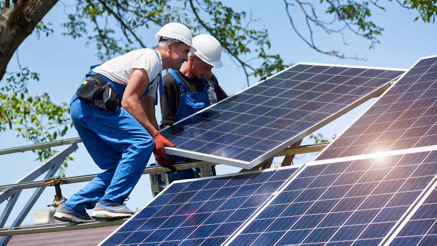 workers carrying solar panels on roof