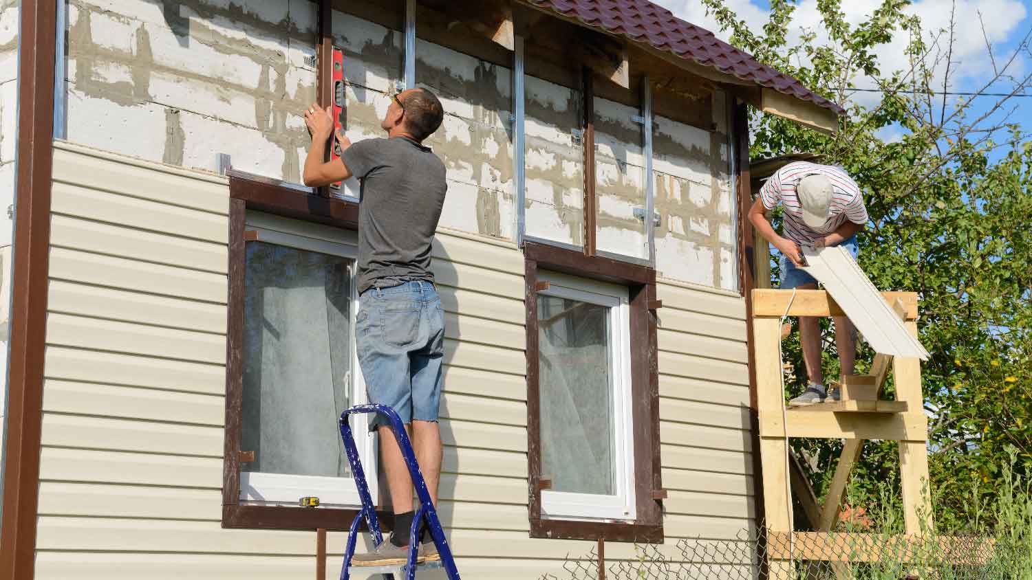 Workers installing cladding to a house