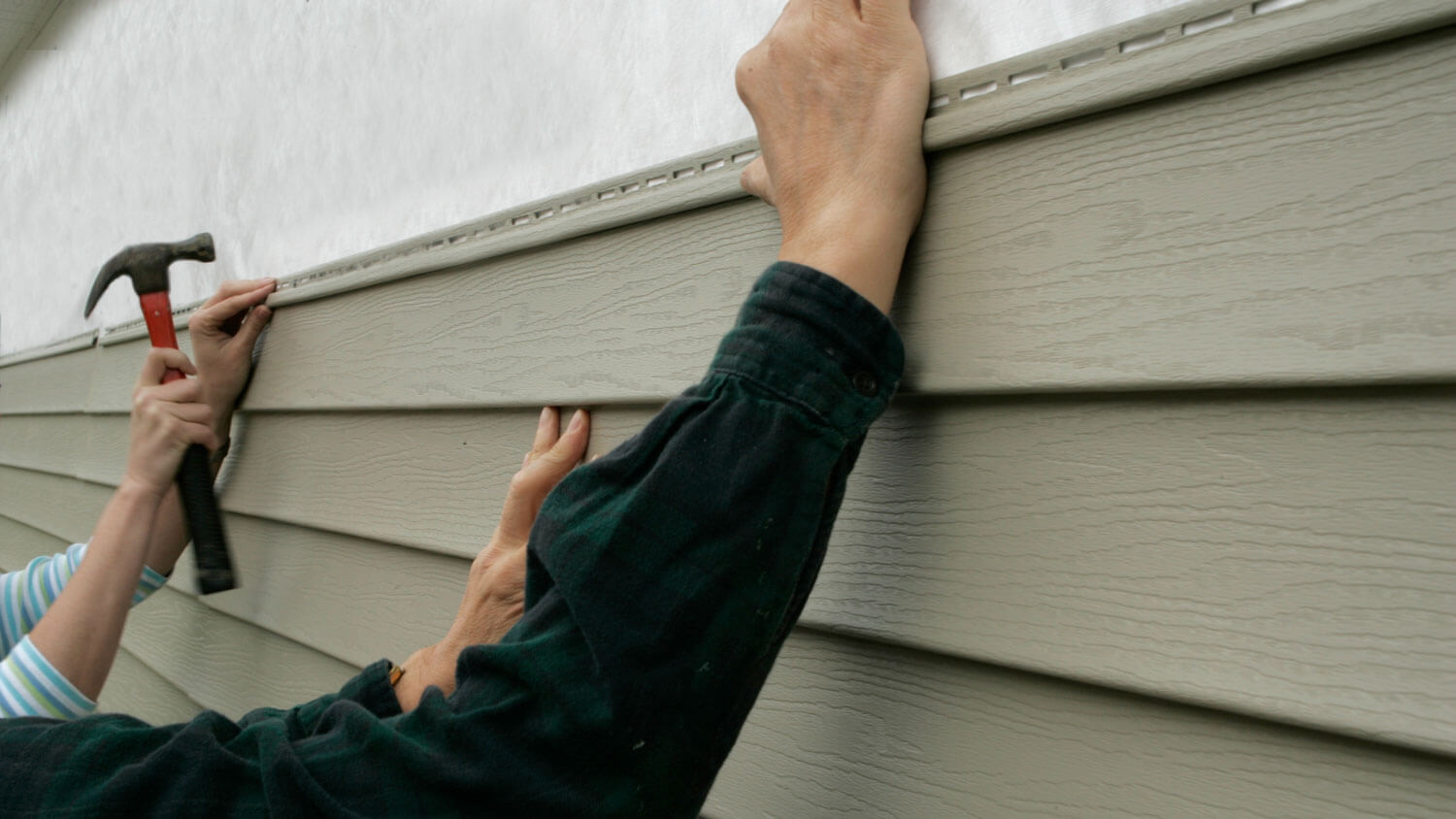 Two workers installing new vinyl siding