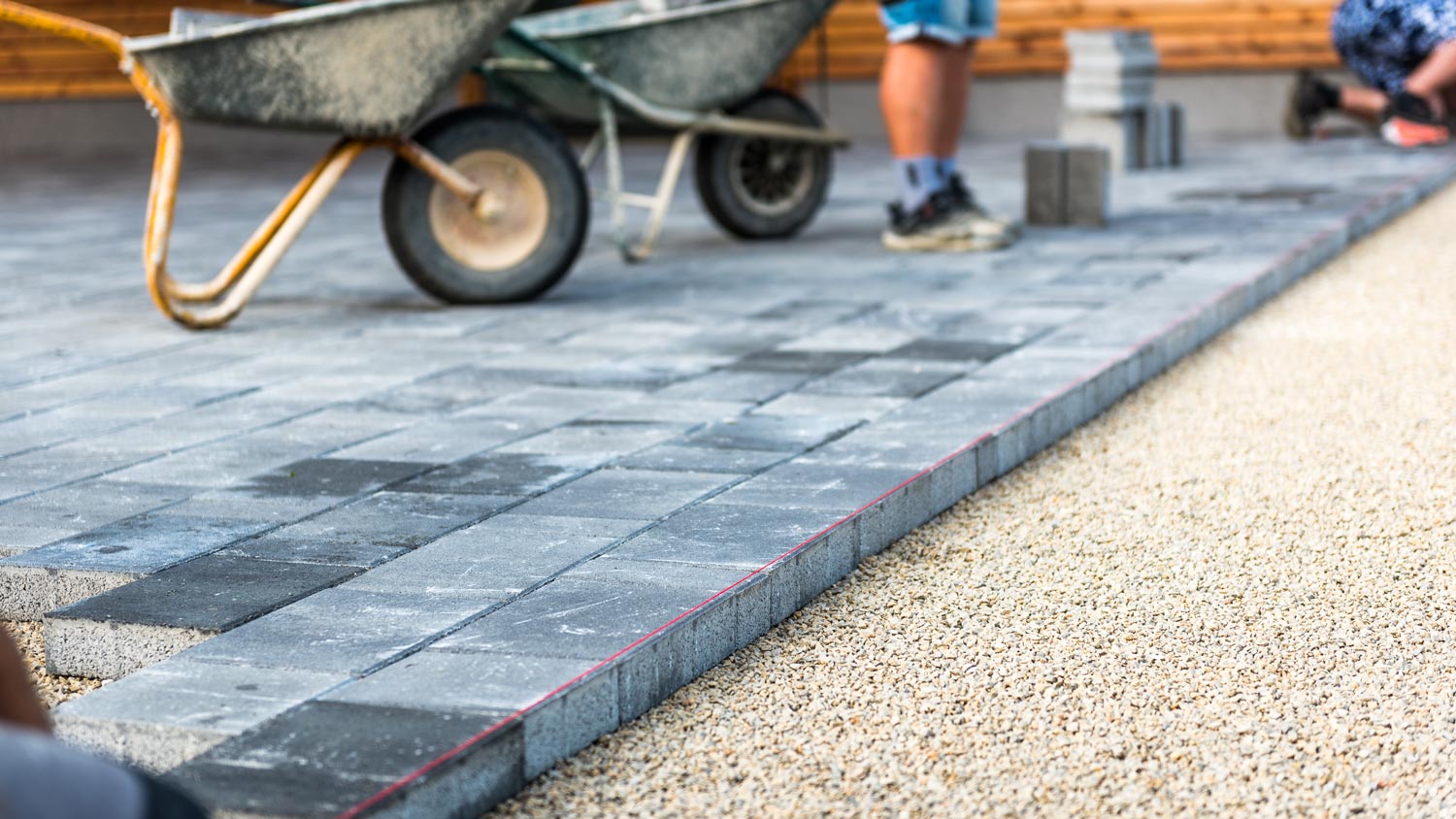 Workers laying bricks on a house’s driveway