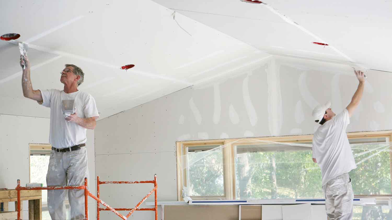 Workers mudding and taping new drywall