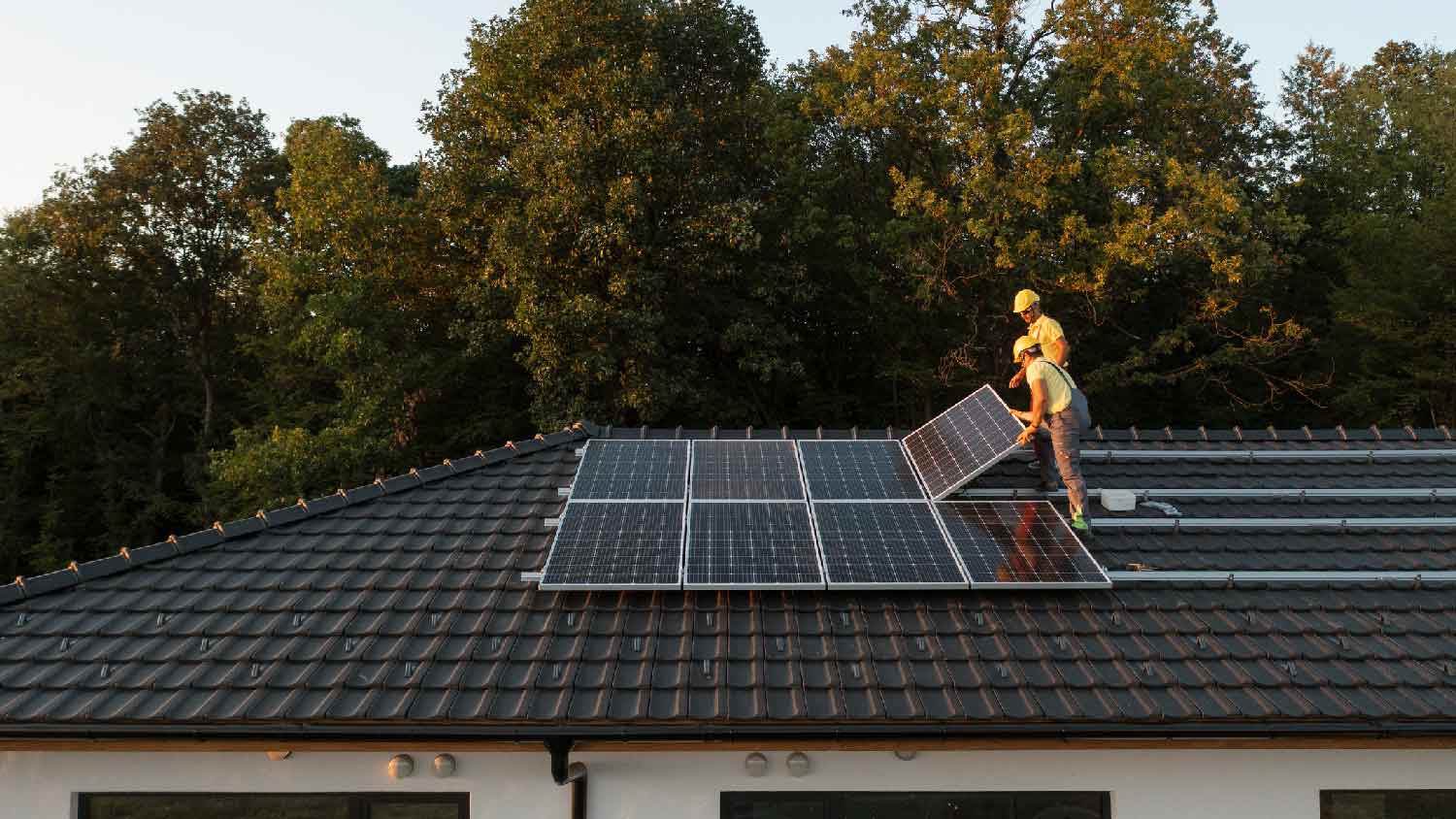 Two workers re-installing solar panels on a roof