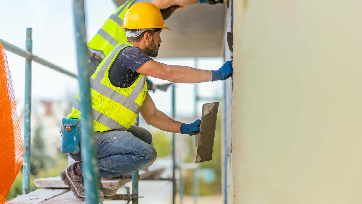 The workers repairing a stucco wall