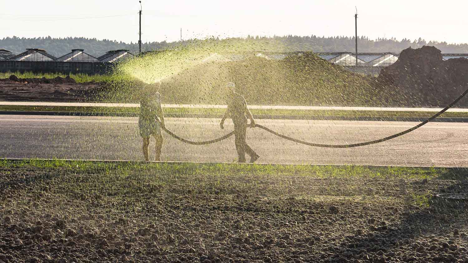 Workers praying soil with hydroseed slurry