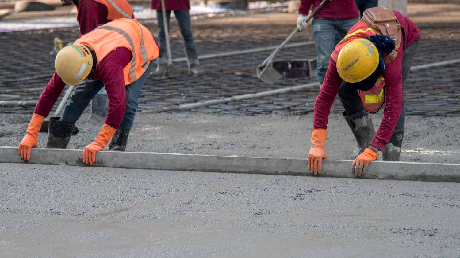 Two workers trowelling wet concrete foundation