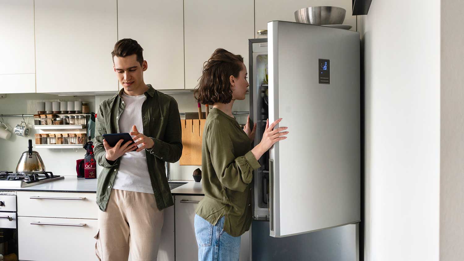 Young couple in the kitchen working on a grocery list