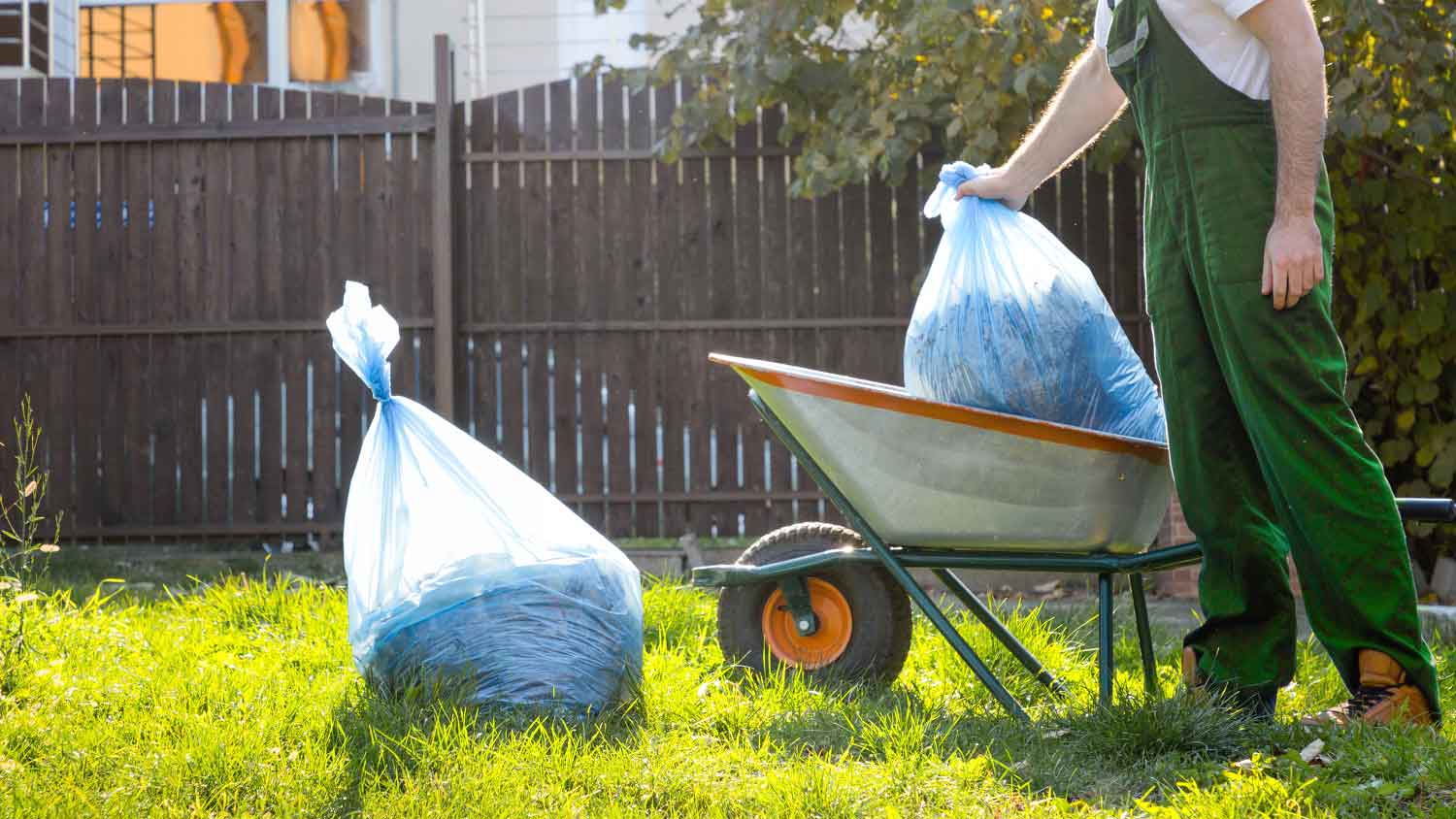 Worker putting bags with mulch in wheelbarrow