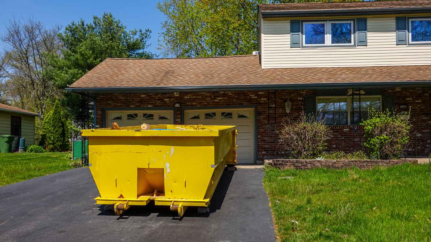 A yellow dumpster in front of a house