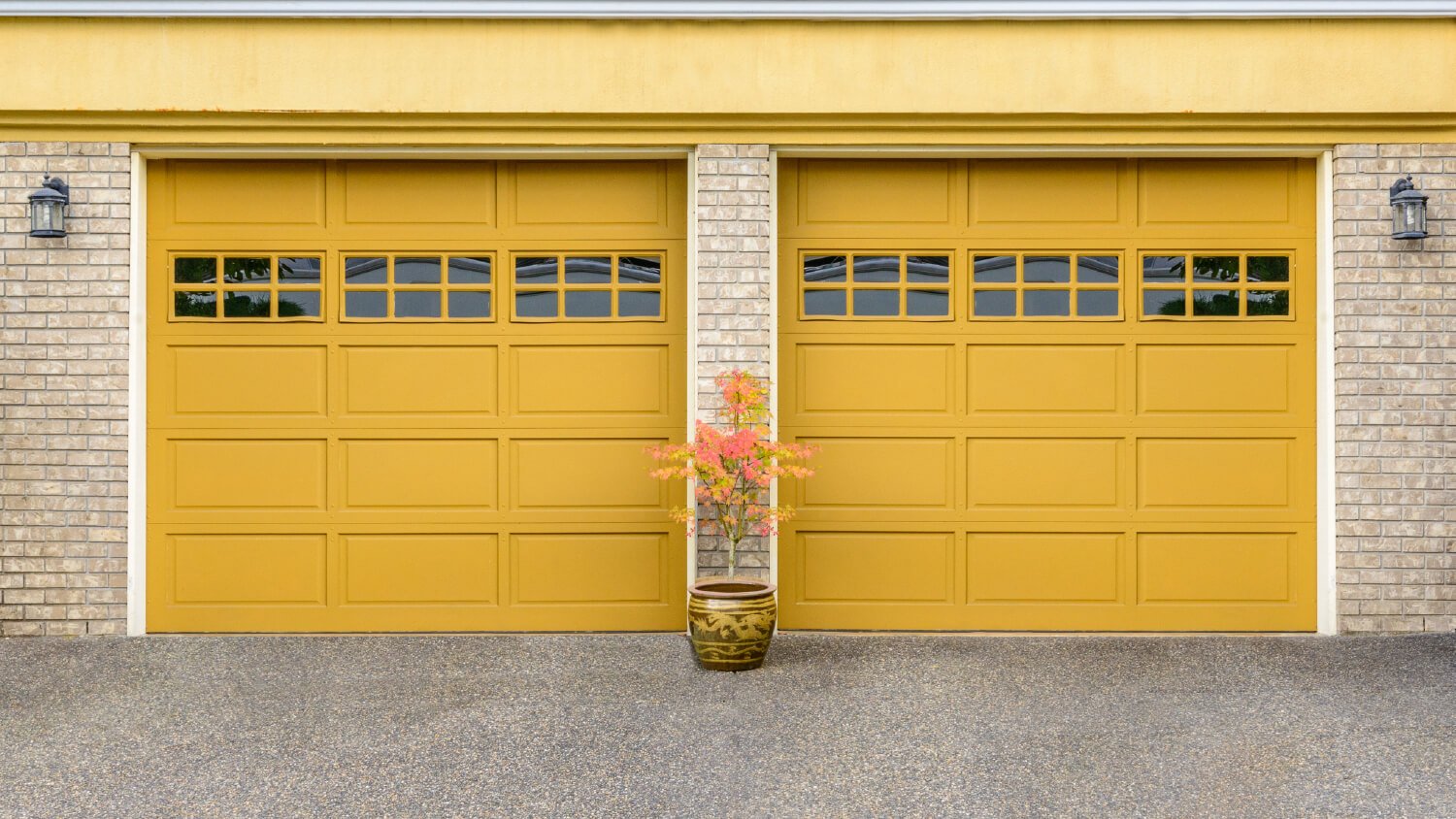 yellow garage doors with potted plant between