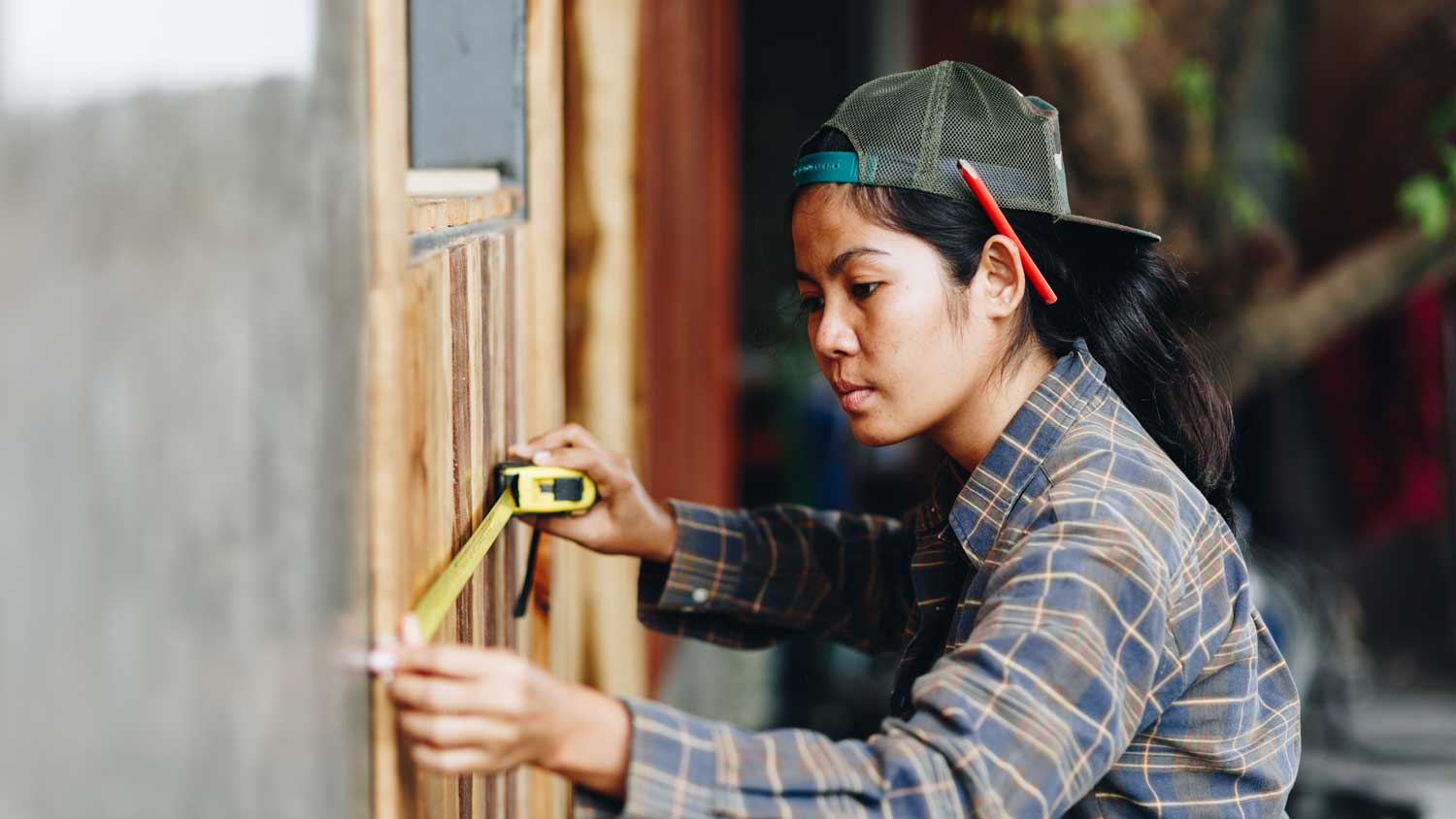 A young woman using measuring tape to mark a wall