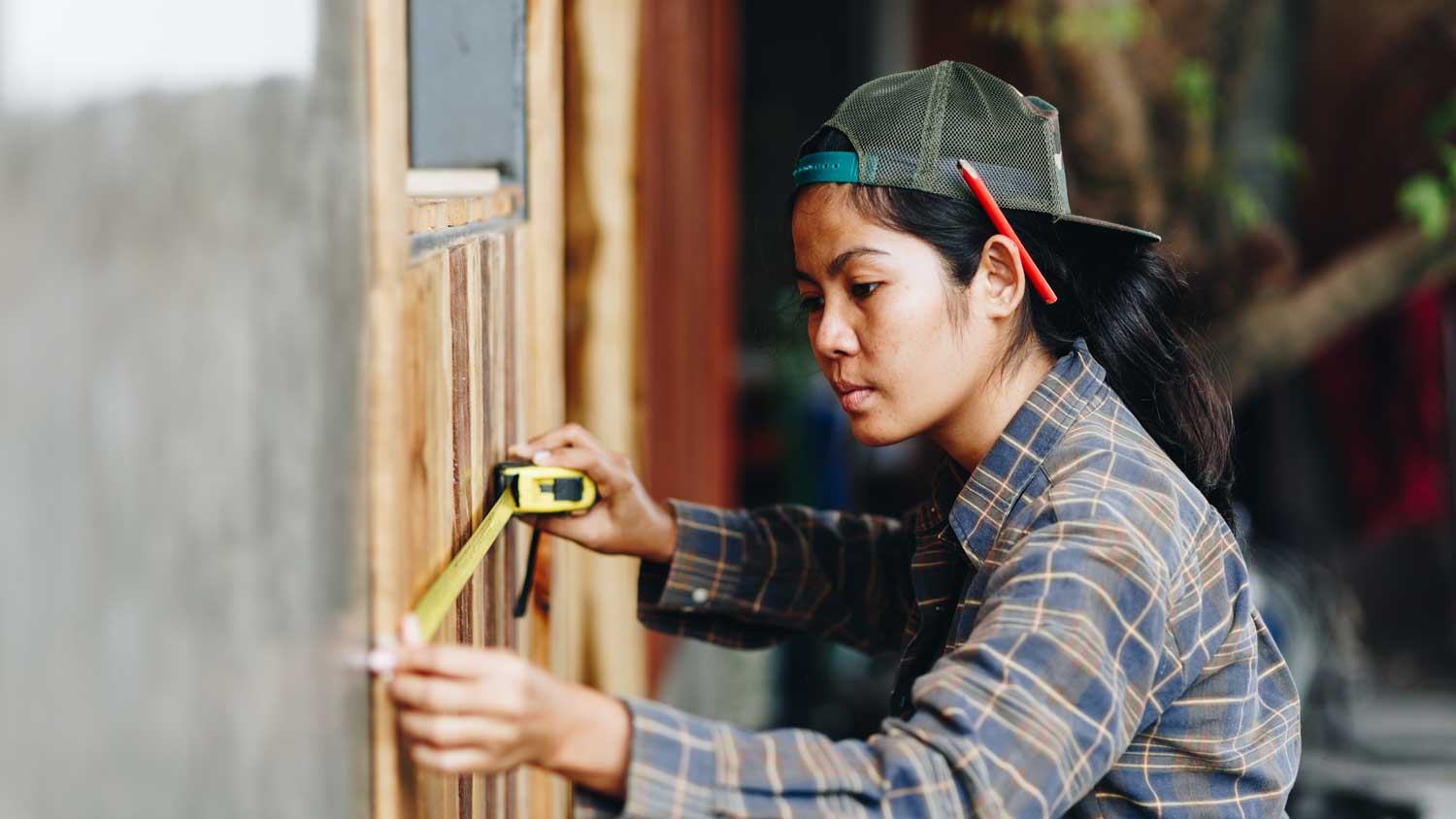  A young woman using measuring tape to mark a wall