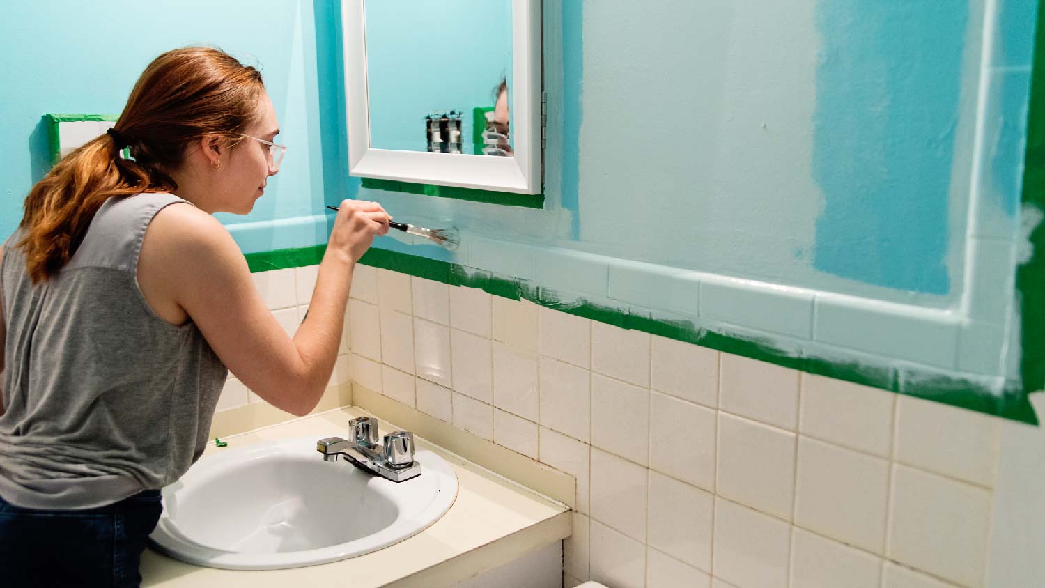 A young woman painting her bathroom