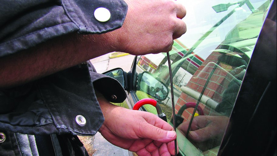 man holding unlocking tool at vehicle window