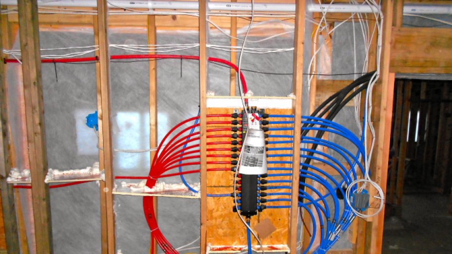 Red and blue PEX plumbing pipe installed in a wall under construction.